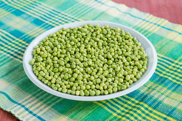 Fresh green peas in a ceramic bowl on table.