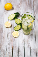 Water with lemon, mint and cucumber on wooden light background. Water Detox.