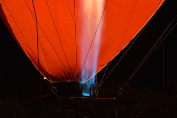 The flames caused by the gas spur up to blow the air into the balloon. The backdrop is black and orange.