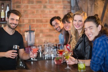 Portrait of bartender serving drinks to happy customers