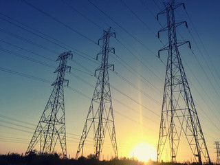 Power line poles pylons over setting sun
