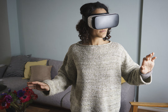 Woman using virtual reality headset while standing in living room