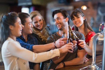 Cheerful friends toasting beer bottles
