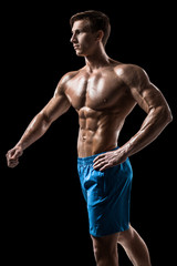 Fototapeta premium Muscular and fit young bodybuilder fitness male model posing over black background.