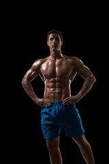 Fototapeta premium Muscular and fit young bodybuilder fitness male model posing over black background.