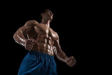 Fototapeta na wymiar Muscular and fit young bodybuilder fitness male model posing over black background.