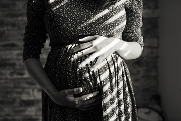 Pregnant woman touching her belly. Black and white close-up shot.