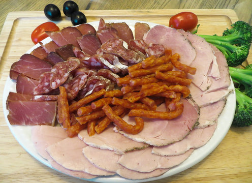 Sliced ham, salt, and smoked meat with vegetables.