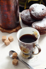 A cup of coffee and freshly baked chocolate muffins.