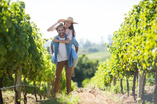 Portrait of happy couple piggybacking at vineyard