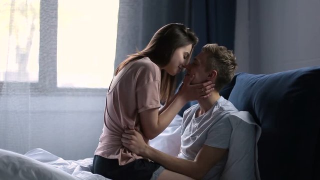 Loving couple on bed in affectionate sensual kiss