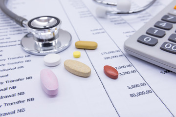 Stethoscope and medicine on bank statements background, concept financial health.