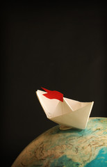 Travel concept with globe and paper boat