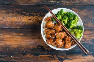 Chicken teriyaki, rice and broccoli in a white big bowl with chopsticks above. Wooden rustic table, top view. - 146100819