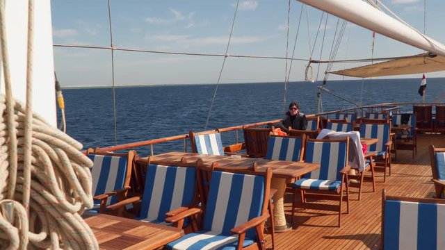 A woman sits at a table on the open deck of a sailing yacht. Sinai Egypt