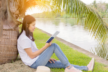 young beautiful woman relaxing in park nearby lake