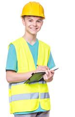 Emotional portrait of teen boy wearing safety jacket and yellow hard hat. Happy child with notebook and pen writing something, isolated on white background. Funny cute guy construction worker.
