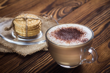A cup of coffee and small cookies on an antique wooden table