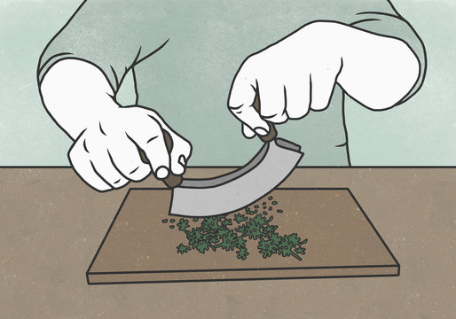 Midsection of man cutting herbs with mincing knife on chopping board