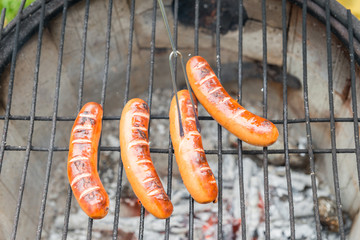 Grillrost mit Würstchen auf einem alten Feuertopf mit brennendem Feuer