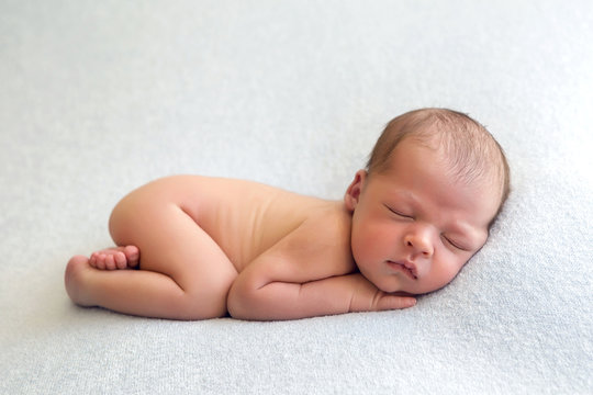 Newborn baby boy naked lies on a light blanket