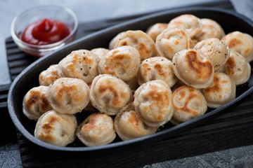 Close-up of russian roasted pelmeni served in a frying pan, selective focus