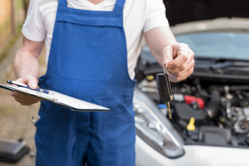 Mechanic delivering car keys after car engine checking