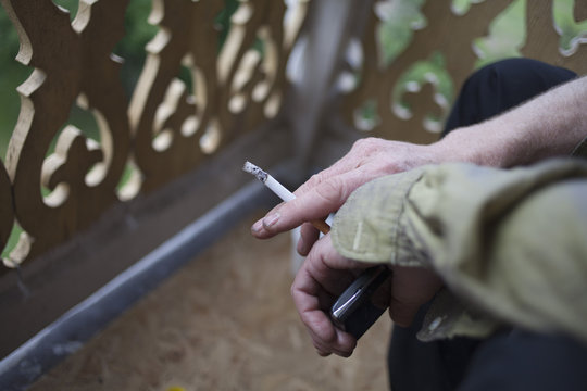Cropped image of man holding cigarette and mobile phone