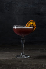 Cocktail with foam in a transparent glass on a high leg, decorated with a dried citrus slice