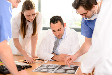 group of surgeons and medical professional staff discussing on patient radiography outside hospital operating room