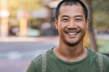 Handsome Asian man standing on a city street and smiling