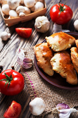 Hearty and tasty food, national Ukrainian cuisine, pies made of yeast dough with mushrooms, tomatoes and spices on rushnyk on a dark rustic wooden background  
