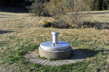 Quellfassung aus Edelstahl auf einer Wiese im Schwarzwald für die lokale Wasserversorgung in ländlicher Umgebung