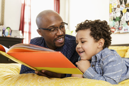 Father reading book to son on bed