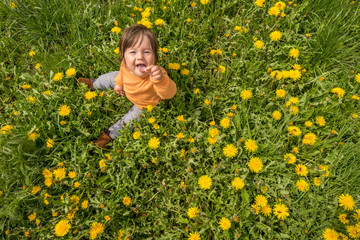 Cute white girl playing on a meadow full with yellow flowers during springtime