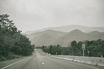 long straight road with mountain view of countryside haze freeway photography in black and white