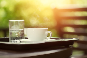 coffee in the morning with water glass, cup of espresso on wood table in cafe or coffeeshop.