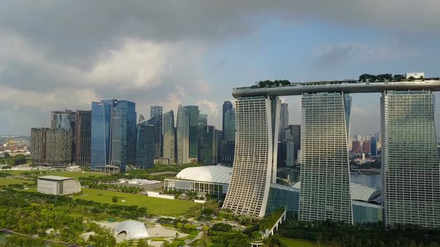 4k travelling aerial shot of Marina Bay Sands with Singapore City Skyline as background during cloudy summer day