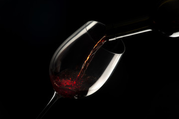 glass with red wine on black background