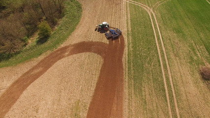 
aerial view of a tractor at work on agricultural fields -  tractor cultivating a field in spring