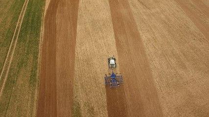 
aerial view of a tractor at work on agricultural fields -  tractor cultivating a field in spring