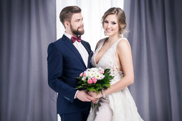 Newlyweds in a wedding dress and a suit stand in a ballroom