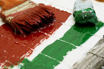 Brushes in green and red paint on a white background