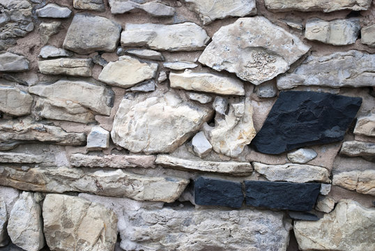 Alte Natursteinmauer mit zwei schwarzen Steinen, Textur, Hintergrund, Textfreiraum