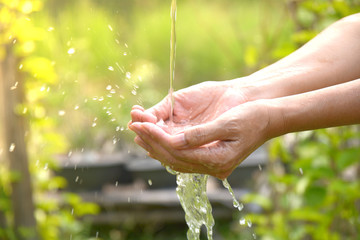 Water pouring in woman hand on nature background.