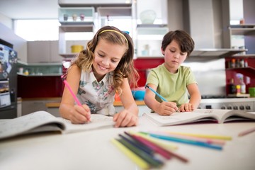 Siblings doing homework in kitchen