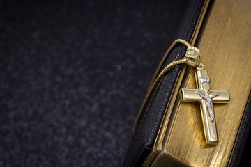 Gold cross and Bible on a dark background. Free space for text.