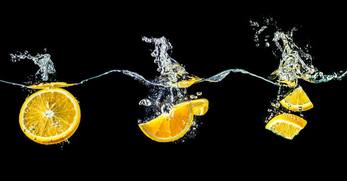 Composition of three oranges falling into water close-up, macro, splash water, bubbles, isolated, black background. Big large size.