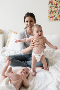 Caucasian mother playing with twin baby daughters on bed