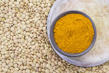 Pile of lentils y turmeric on wooden background (Lens culinaris)
